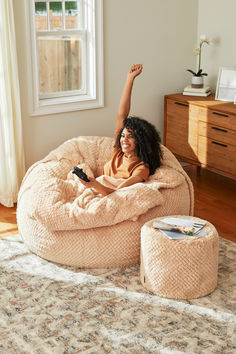 a woman laying on top of a bean bag chair in a living room next to a window