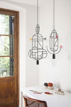 two black and white lights hanging from the side of a wall next to a window