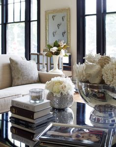 a living room filled with lots of furniture and flowers on top of a coffee table