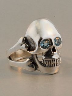 Any pirate would be proud to wear this solid sterling silver and beautifully detailed Skull and Cross Bone Ring. The skull is 1 1/8" in length and the the substantial band is formed by a pair of crossbones. It is pictured here with both Blue Topaz and Citrine options set in the eyes. It is also available with Amethyst, Peridot, or Mozambique Garnet, or for an additional price, Rhodolite Garnet, Rainbow Moonstone, Mexican Fire Opal, Sapphire, Ruby, Tsavorite or Diamond.  Please select your desire Topaz Eyes, Topaz And Citrine, Pirate Jewelry, How To Wear Rings, Biker Jewelry, Bone Jewelry, Blue Topaz Gemstone, Skull Jewelry, Casting Jewelry