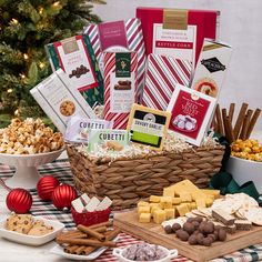 an assortment of holiday treats and snacks on a table with a christmas tree in the background