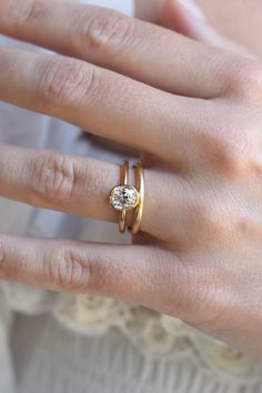 a woman's hand with two gold rings and a diamond ring on her finger