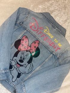 a jean jacket with minnie mouse on it and the word disney written in pink glitter