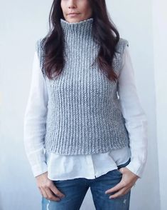 a woman standing in front of a white wall with her hands on her hips and looking at the camera