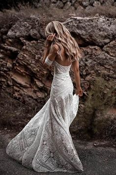 a woman in a white dress walking down the road with her back to the camera