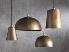 three brass colored pendant lights hanging from a gray wall in a restaurant or bar area