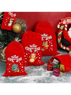 red christmas bags with santa claus on them sitting next to a tree and other decorations