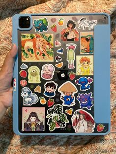 someone is holding an ipad with many stickers on the cover and it's case