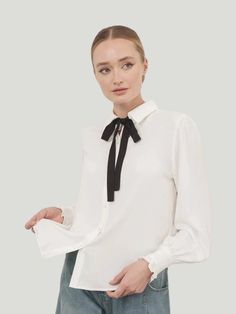 Elevate your style with the exquisite Aaron & Amber Quinn Classic Bow Tie Blouse from Aaron & Amber. This chic blouse combines function and fashion with its crinkle-woven fabric, highlighted by a contrasting bow tie that adds a touch of sophistication. The button-down design, complete with cover buttons, ruffled sleeve cuffs, and a classic collar, exemplifies timeless elegance, making it a must-have for any fashion-conscious individual. Additional Details: Product Type: Tops Style: Lon Sleeve Blouse Color: White w/ Black Necktie Material: 100% Polyester Care: Hand wash Eco-Conscious Brand Women Owned Amber Quinn, Black Necktie, Bow Tie Blouse, Workwear Essentials, Tops Style, Chic Blouses, Bow Blouse, Long Jumpsuits, Ruffle Collar