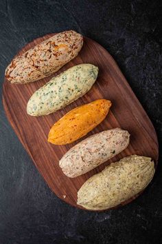 four different types of bread on a wooden platter with black stone background, top view