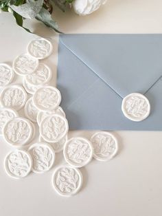 a blue envelope with white wax seals and flowers on the table next to an envelope