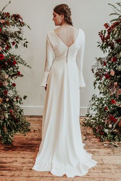 the back of a woman wearing a white wedding dress with long sleeves and open shoulders