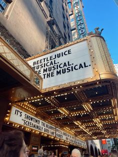 the marquee for beetle movie is lit up in front of a building with people walking around it