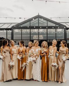 a group of women standing next to each other wearing dresses and holding bouquets in their hands