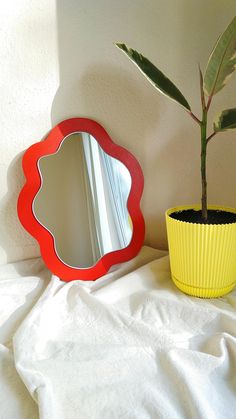 a potted plant next to a mirror on a bed