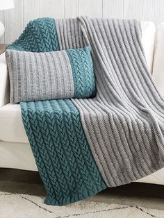 a white couch sitting next to a blue and gray blanket on top of a wooden table