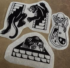 three black and white stickers with different designs on them, one is a cat