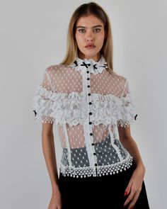 Introducing the elegant Alicia Blouse, crafted from Swiss Point D’Esprit with cotton lace ruffles, Venise trims, and satin baby bows. This soft, fitted blouse features an empire focus, adorned with delicate ruffles at the neckline and sleeves, complemented by satin pearl buttons at the center front. Available in White and Black or Black on Black. Swiss Point D’Esprit Cotton lace ruffles with Venise trims Satin pearl buttons Dry clean only Each piece is made to order and handcrafted in our atelie Tap Shorts, Fitted Blouse, Fitted Blouses, Black On Black, Lace Ruffle, Pearl Buttons, Baby Bows, Cotton Lace, Summer 2024