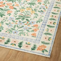 an area rug with flowers and leaves on the floor in front of a wooden floor