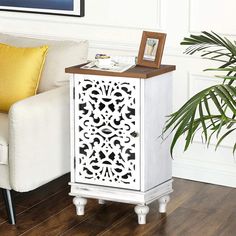 a white cabinet sitting on top of a hard wood floor next to a chair and potted plant