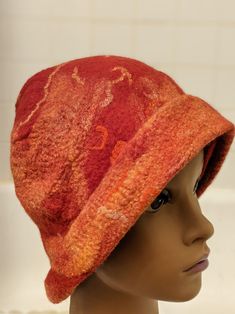 This hat is red with orange and yellow.  It is a cross between a beanie and a cloche style hat.  I made this from merino wool roving, with silk and pieces of yarn all felted to a single, seamless piece.  I love the warm colors reminiscent of a sunset.  In addition to the warm colors, the hat itself will keep one warm on a chilly day or evening. The hat was made using a wet felting process which involves laying out the roving and other fibers and then manipulating while it is wet and soapy by hand for several hours before finally shaping it and letting it dry for a day. This is one of a kind, wearable art.  It would make a perfect gift for someone who loves unique accessories. Red Beanie Hat, One Size Fits Most, Red Short Brim Cloche Hat For Fall, Red Beanie For Fall, One Size Fits Most, Warm Red Hat, One Size Fits Most, Red Wool Felt Hat With Curved Brim, Red Wool Felt Hat For Winter, Red Felt Hat With Curved Brim, Red Felt Hat With Curved Brim, One Size, Red Wool Winter Hat