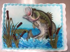 a cake decorated with a fish and reeds on top of a metal wall panel