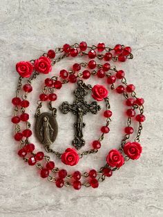 A beautiful handcrafted Catholic five decade tradition style chains prayer rosary. It's a great and thoughtful gift for someone special.  Made with red 6mm crystal beads for the decades, and optional red rose accent 10mm beads for the Our Father's. If without roses is desired the rose beads will be replaced with the red crystal.  You have the option of Silver or Bronze for the metal Crucifix and Virgin Mary medallion. Each rosary is handmade in Florida with love.  Customized rosaries are availab Handmade Red Rosary For Jewelry Making, Handmade Red Crucifix Jewelry, Spiritual Red Crucifix Rosary, Spiritual Rosary As Valentine's Day Gift, Red Spiritual Rosary As Gift, Handmade Red Rosary With Cross, Handmade Red Cross Rosary, Handmade Red Rosary, Red Crucifix Rosary As Gift