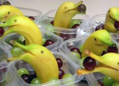 plastic containers filled with grapes and bananas as if they're eating fruit from the same container