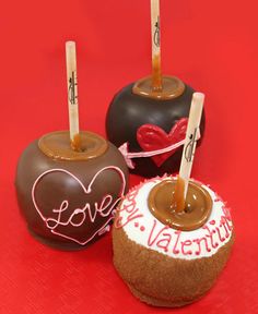 three chocolate covered donuts sitting on top of a red tablecloth next to each other