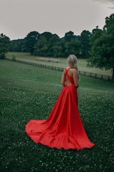 a woman in a red dress is standing in the grass