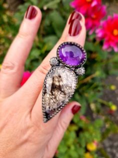 A beautiful, bold talon ring, completely handmade from recycled sterling silver. It holds a deep purple amethyst that seems to glow in the light, and a delicately patterned plume agate stone, with a subtle shimmer and hint of purple. A gorgeous match of stones, this ring is a real statement piece! It sits on a wide, adjustable ring band. All metal is eco solid sterling silver and fine silver and it has been oxidised for a dark, and slightly gothic finish. Silver Amethyst Ring In Mystical Style, Mystical Sterling Silver Amethyst Ring, Purple Mystical Jewelry Ring, Mystical Amethyst Ring In Sterling Silver, Mystical Sterling Silver Rings In Purple, Mystical Sterling Silver Jewelry With Large Stone, Fusion Style Amethyst Gemstone Rings, Amethyst Gemstone Fusion Rings, Mystical Sterling Silver Purple Rings