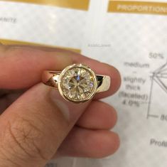 a person holding a ring with a diamond in it's center and on their finger