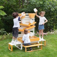 three children are playing with a toy house made out of pallets