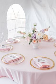 the table is set with pink and gold plates