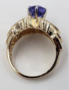 Title: Oval Tanzanite and Diamonds in 14 Kt Yellow Gold Ring Size 6. 1/2 US DesignerUnbranded MaterialYellow Gold 14Kt Stamped Style: Vintage Gemstone Details All measurements are approximate and may vary slightly from the listed dimensions. Diamonds: Cut: Round Diamonds 30 Estimated Size 1.8 mm and 1.5 mm average approximated 0.55 CTW Estimated Color: G-H Clarity: VS Tanzanite: 9.24 mm/7.04 mm/4.22 mm 1.93 CT Estimated Measurements Length/Width/Depth 20.52 mm/12.55 mm/8.47 mm Estimated Total We Exquisite Gold Sapphire Ring With Accent Stones, Exquisite Gold Multi-stone Sapphire Ring, Gold Tanzanite Round Rings, Gold Round Cut Gemstones Fine Jewelry, 14k Gold Gemstones For Anniversary, Round Gold Gemstone With Center Stone, Gold Tanzanite Rings With Accent Stones, Gold Tanzanite Rings For Anniversary, Formal Gold Gemstones In 14k Gold