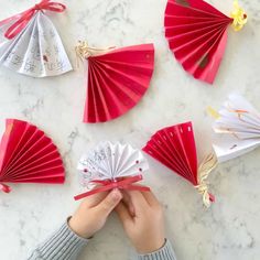 someone is holding some paper fans in front of their hand and the other one has a red ribbon around it