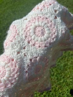 a pink and white crocheted hat sitting on top of green grass