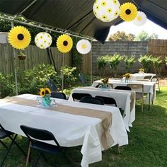 an outdoor dining area with tables, chairs and sunflowers hanging from the ceiling