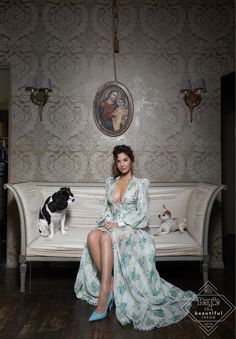 a woman sitting on a white couch next to a black and white dog