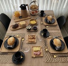 a table set for breakfast with breads, muffins and other food items