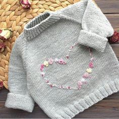 a sweater with flowers on it sitting next to a basket