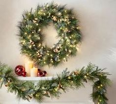 christmas wreaths and candles are arranged on the mantle