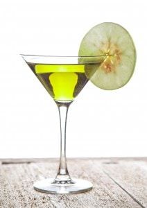 an apple sitting on top of a martini glass filled with liquid and garnish