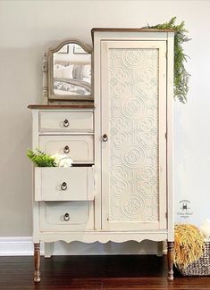 a white armoire sitting on top of a hard wood floor next to a mirror