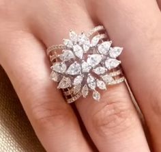 a woman's hand with a ring on top of her finger and an engagement ring in the middle