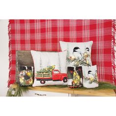 christmas pillows and decorations on a shelf in front of a red plaid wall with pine branches