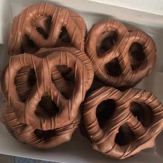 four chocolate doughnuts in a white box on the table, ready to be eaten