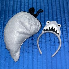 a white hat with a shark's teeth on it and a silver bag that has a black string attached to it