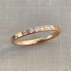 a gold wedding ring with five diamonds on it's side, sitting on a white cloth