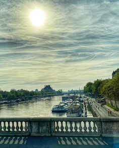 the sun shines brightly over boats on the water near a bridge and some buildings